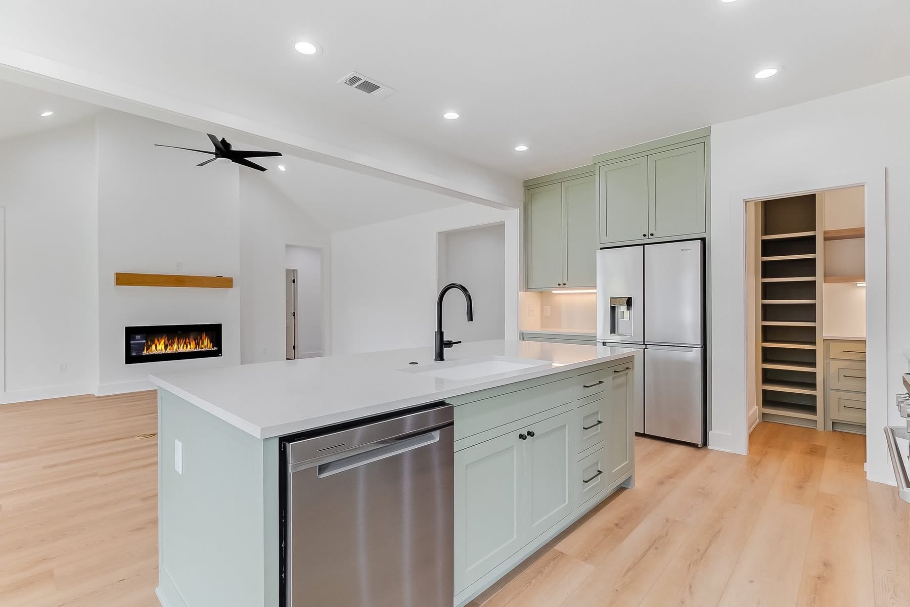 Sage green kitchen with island and fireplace