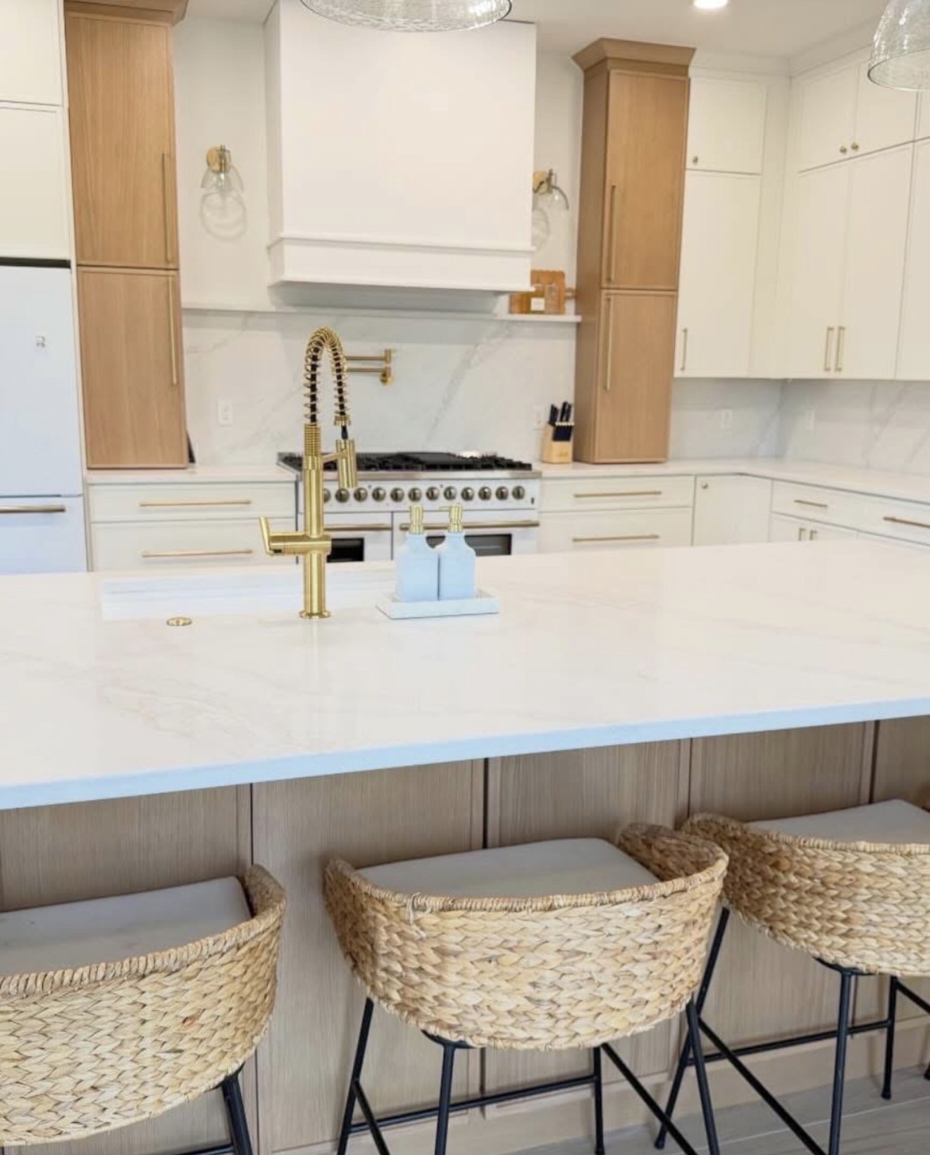 Two-tone white and natural wood kitchen with gold faucet and white range hood — St. Louis remodel by Phoenix Construction Group