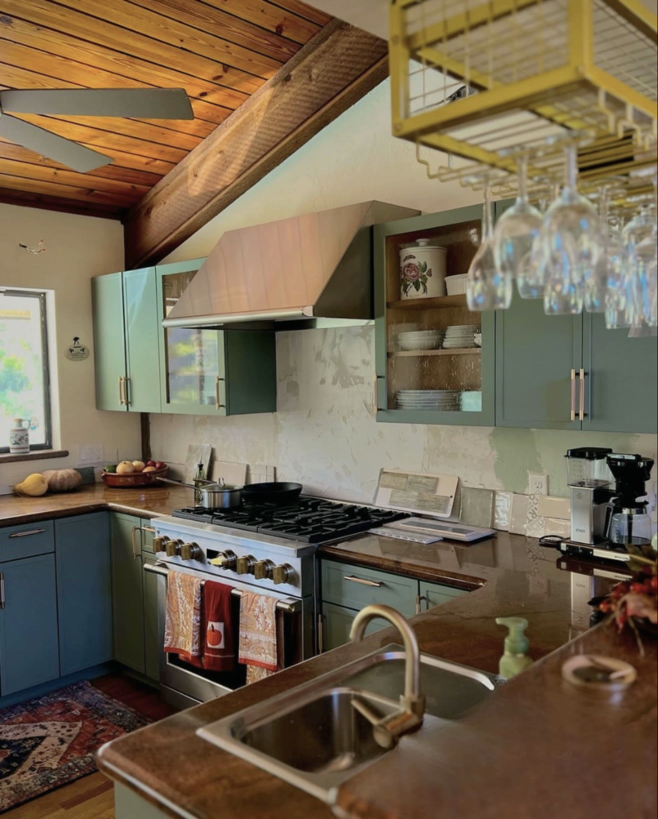 Green kitchen with gold pendant lighting and glass-front cabinets — St. Louis remodel by Phoenix Construction Group