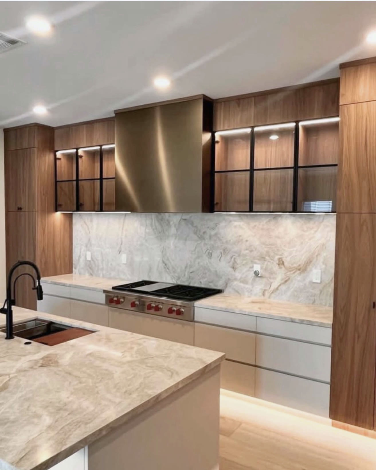 Modern walnut kitchen with marble waterfall island and LED lighting — St. Louis remodel by Phoenix Construction Group