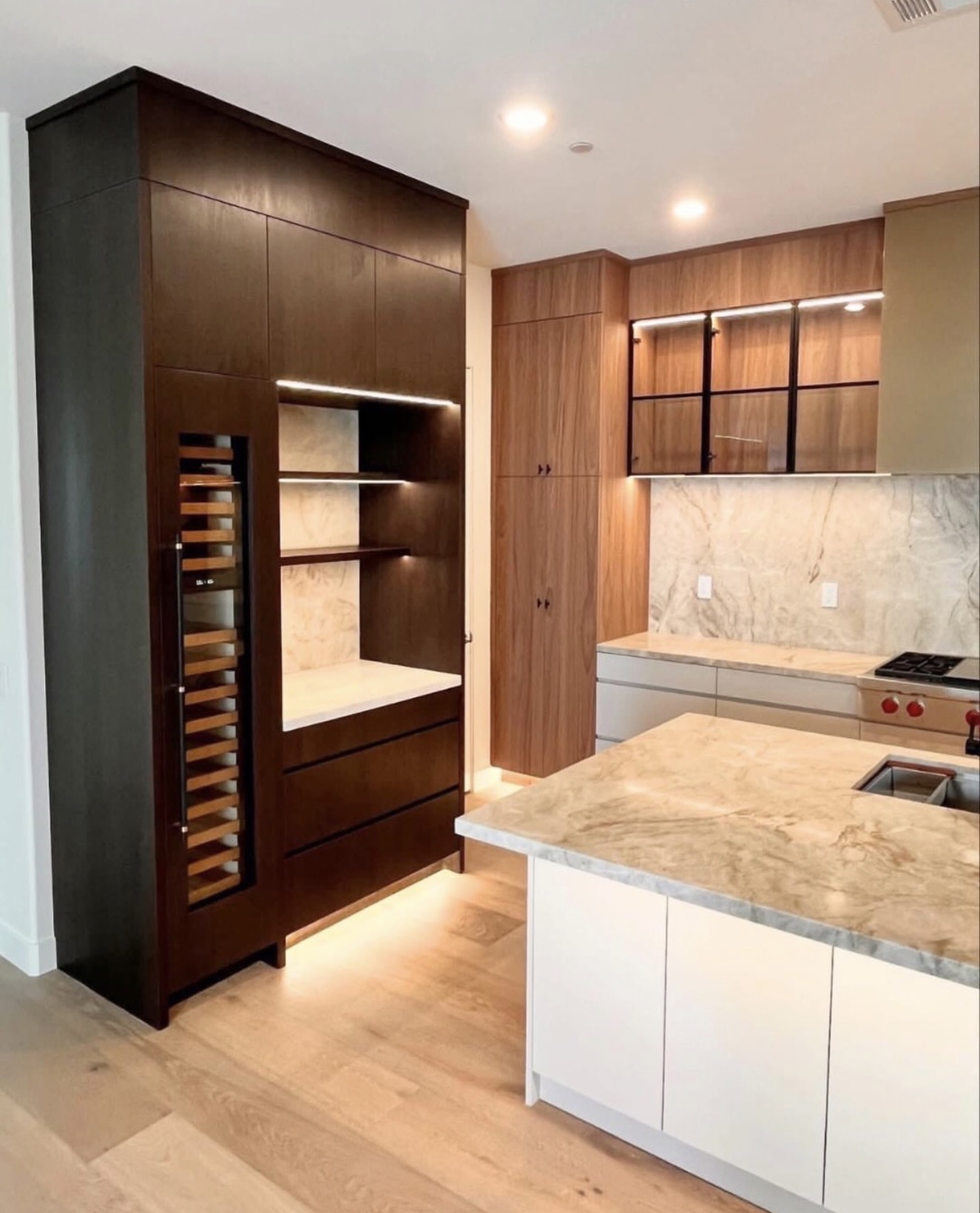 Modern walnut kitchen with built-in wine wall and marble island — St. Louis remodel by Phoenix Construction Group