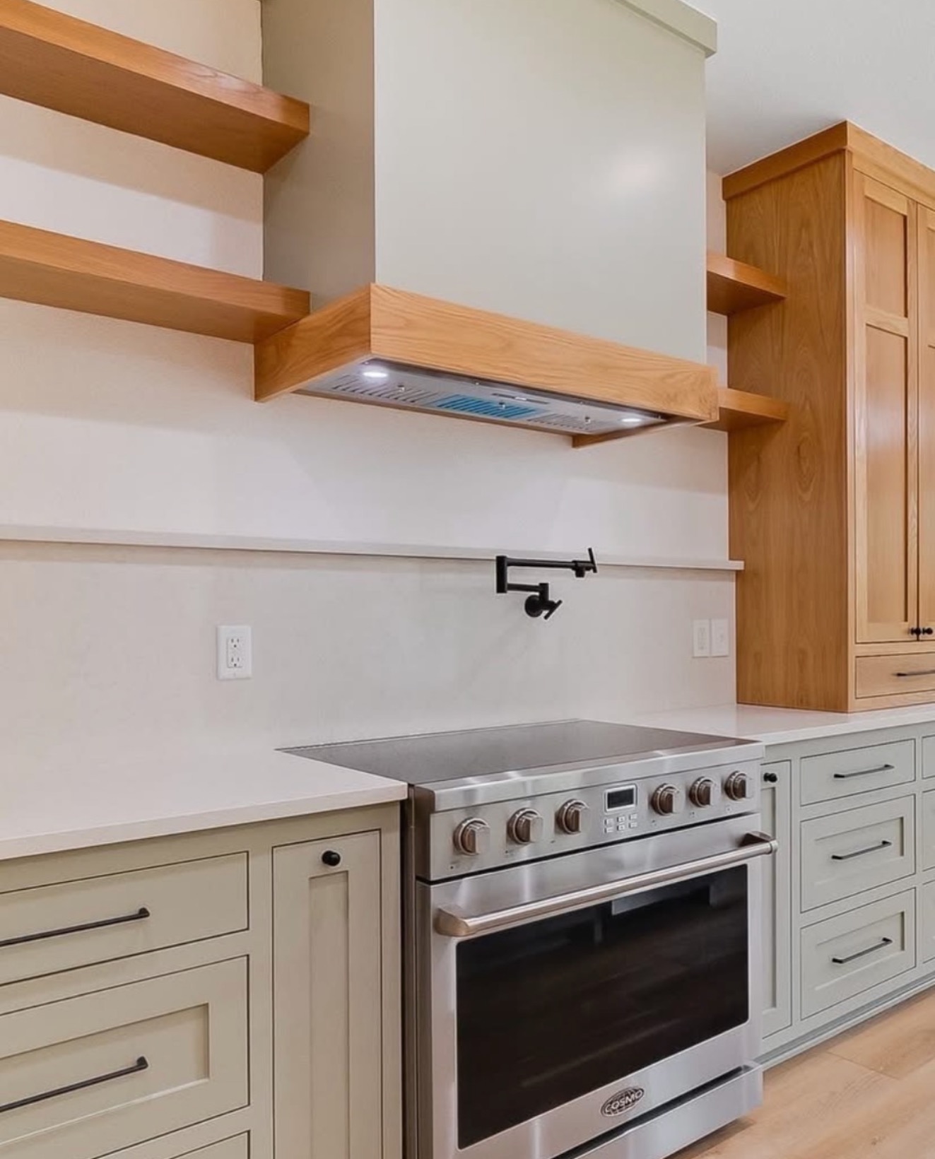 Sage green kitchen with wood shelves and pot filler over the range — St. Louis remodel by Phoenix Construction Group
